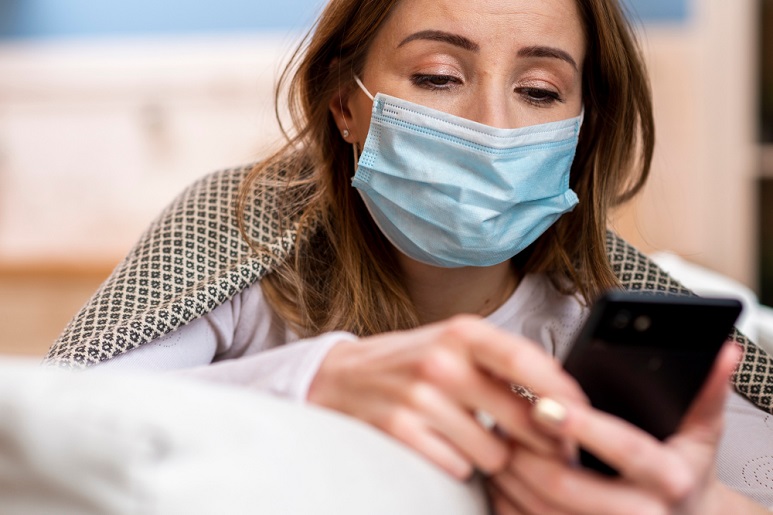 Covid femme avec masque qui regarde son téléphone portable